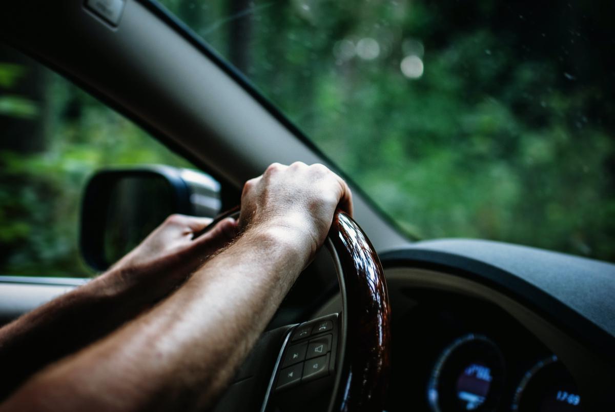 image of a person driving a car with hands on the steering wheel